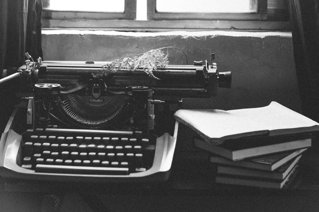 Grayscale Photography Of Typewriter Near Books